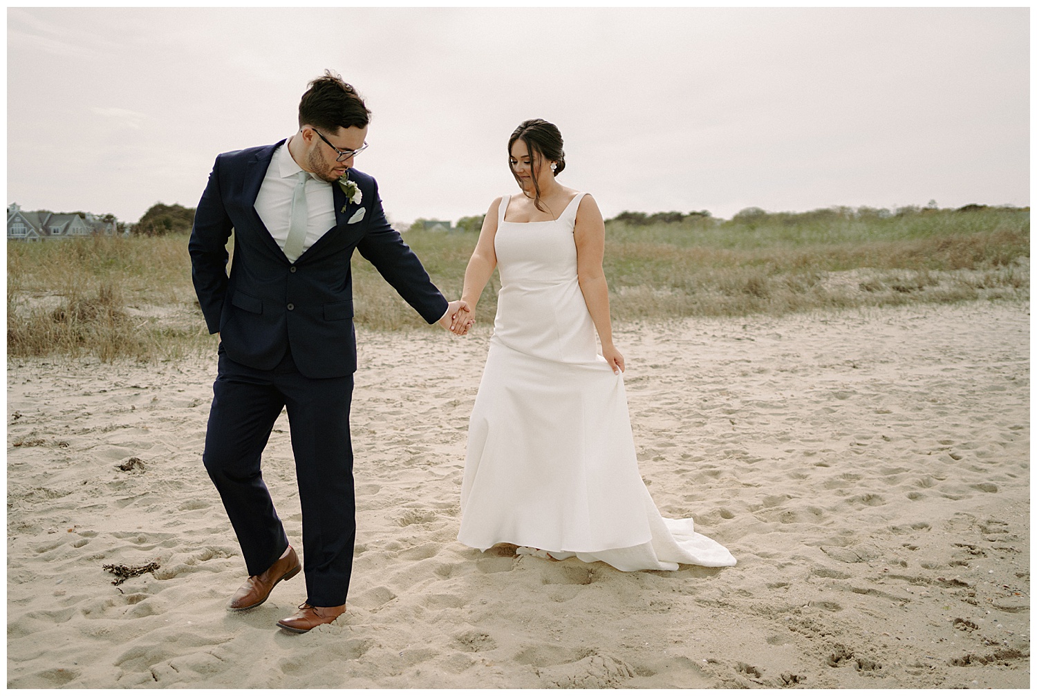 Groom leading bride on sandy beach