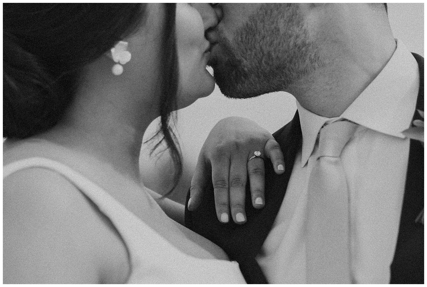Grainy black and white photo of bride and groom with focus on engagement ring