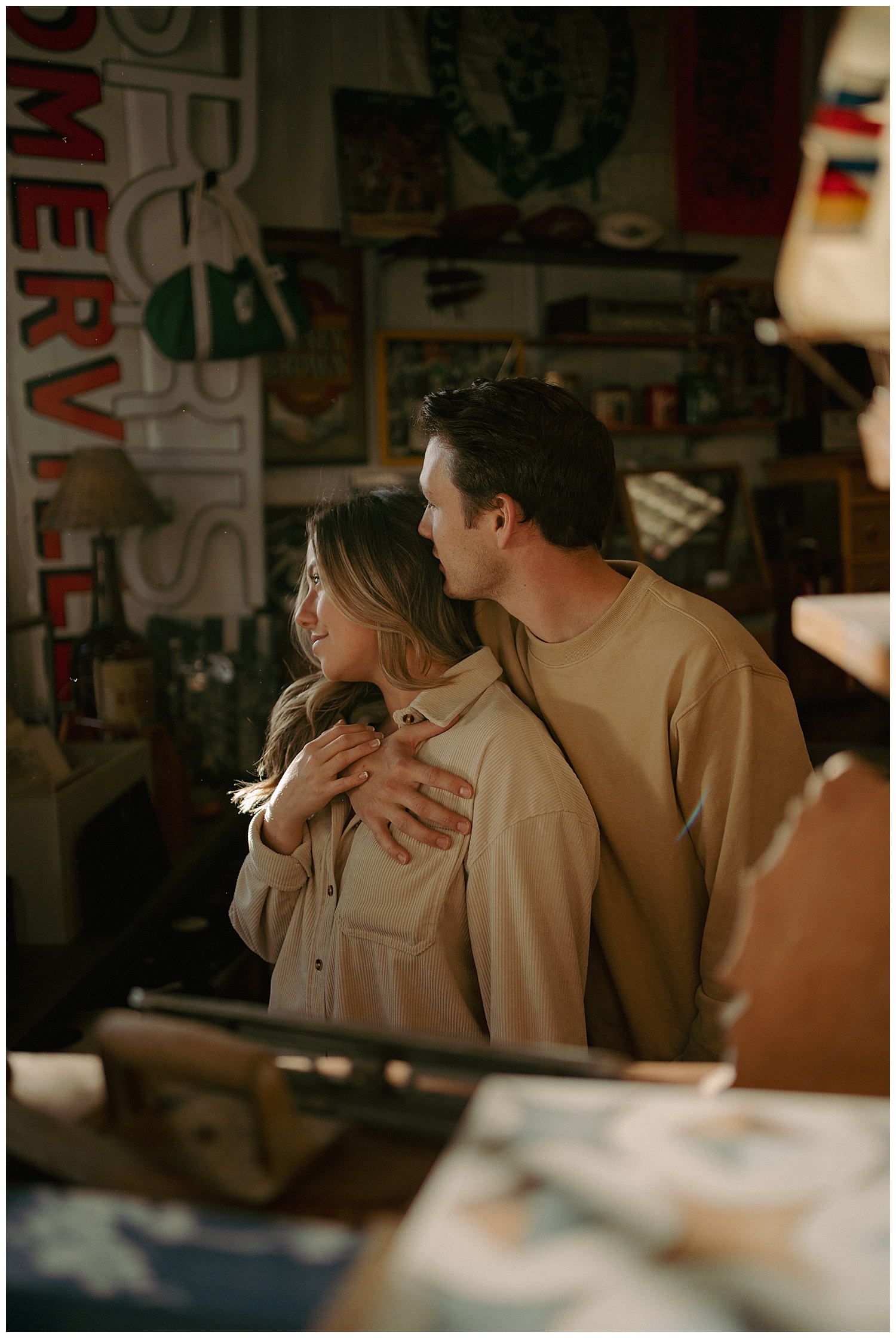 The couple sharing a hug in the antique store window light
